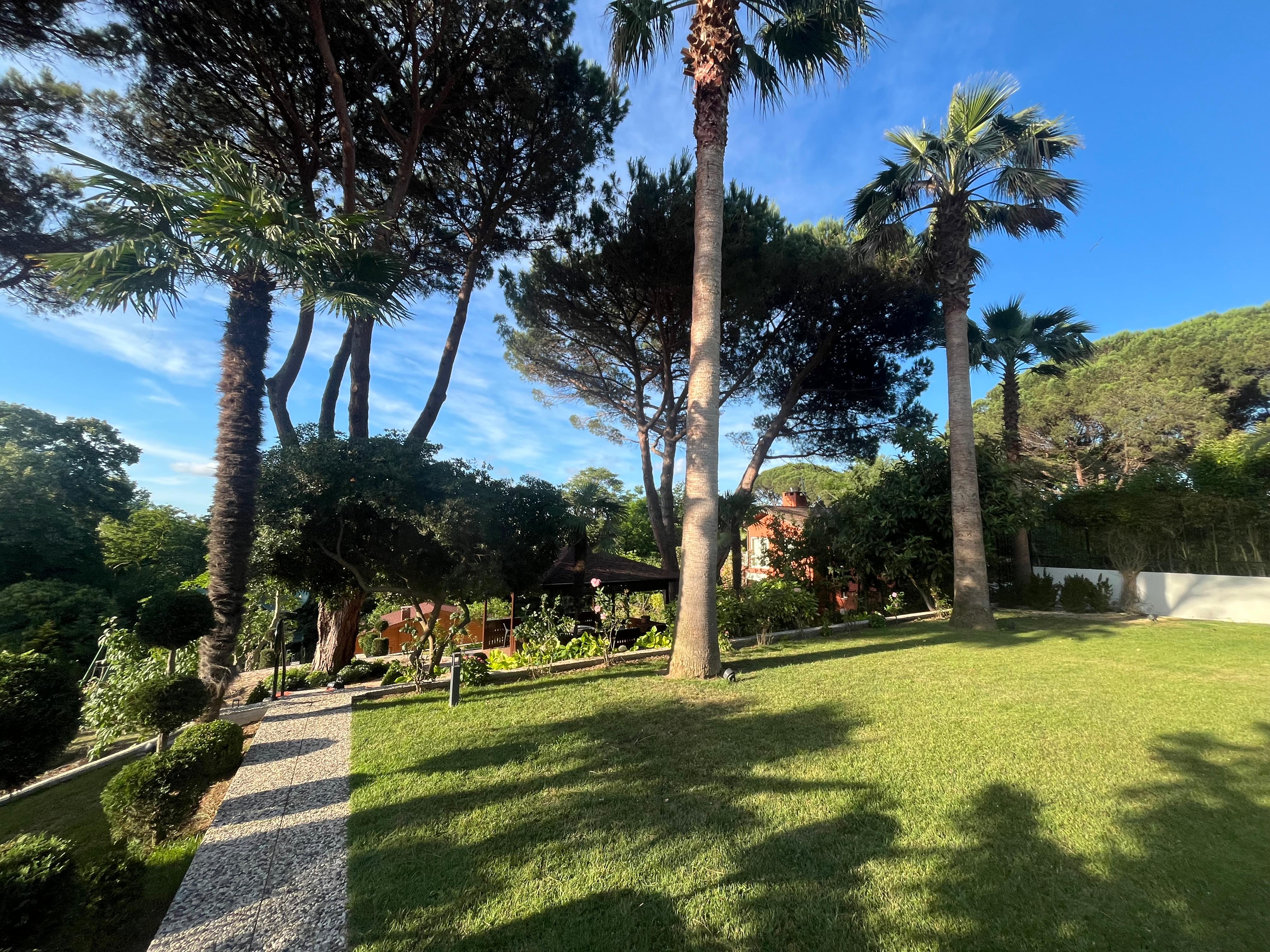 Ülgen Peyzaj tarafından tasarlanmış geniş bir villa bahçesinin gün batımındaki görünümü